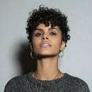 Woman with short, curly hair wearing hoop earrings against a gray background, Obroi