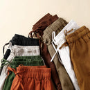 Stack of various colored pants on a beige background, Obroi