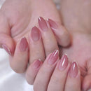 Close-up of hands with glossy almond-shaped nails in a soft pink shade with tiny silver French tips, Obroi