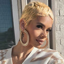 Woman with styled hair and gold hoop earrings standing against a brick wall, Obroi