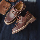 Brown leather shoes with a textured sole on a dark fabric background, Obroi