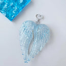 Obroi Light blue angel wings with a heart-shaped clasp on a white background