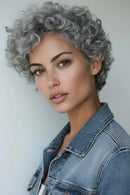 Woman with short, curly gray hair wearing a denim jacket against a plain background, Obroi