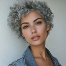 Woman with short, curly gray hair wearing a denim jacket against a plain background, Obroi