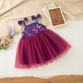 A toddler girl's sleeveless tutu dress with a purple and pink butterfly-patterned bodice and a voluminous magenta tulle skirt, styled in a flat-lay arrangement with a book and flowers on a white sheet, Obroi