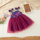 A toddler girl's sleeveless tutu dress with a purple and pink butterfly-patterned bodice and a voluminous magenta tulle skirt, styled in a flat-lay arrangement with a book and flowers on a white sheet, Obroi
