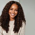 Woman with long, curly hair holding a bundle of hair extensions against a neutral background, Obroi