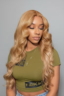 Woman with long blonde hair wearing a green top against a gray background, Obroi