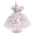 A white girls' party dress with a pastel watercolor floral print, displayed on a dress form mannequin against a white background, Obroi
