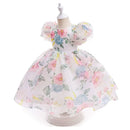 A white girls' party dress with a pastel watercolor floral print, displayed on a dress form mannequin against a white background, Obroi