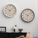 Two wall clocks on a white wall with a desk and decor items below, Obroi