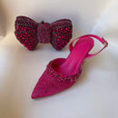 Pink high-heeled shoes with embellishments and a matching pink bow clutch on a light , Obroi