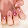 Close-up of a hand with pink nail polish and heart designs on a light background, Obroi