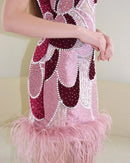 Close-up of a pink and maroon dress with feather details on a neutral background, Obroi