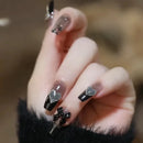 Obroi Hand with black and clear nail design featuring glittery accents against a blurred background