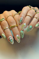 Close-up of a hand with decorative nail art and gold rings, Obroi