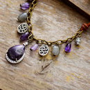 Bracelet with purple beads and silver charms on a wooden surface, Obroi