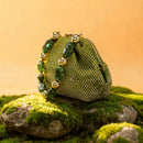Green beaded handbag on a stone with a natural background, Obroi