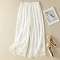 White lace-trimmed pants on a beige surface with a photo frame and shoes, Obroi