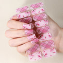 Nail art sticker sheet with pink floral design held by a hand against a beige background, Obroi