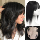 Black wavy wig with straight-cut bangs, shown worn on a model, on a mannequin head, and from underneath to display the attachment base, Obroi