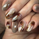 Close-up of a hand with decorative nail art featuring gold and brown elements, Obroi