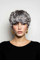 Woman with styled gray hair against a plain background, Obroi