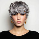Woman with styled gray hair wearing gold earrings against a white background, Obroi