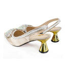 A pair of women's slingback mule heels with metallic gold conical block heels, embellished with iridescent rhinestones on the toe and along the thin straps. The shoes are shown on a clean white background with a 'Obroi' brand logo in the top-left corner, Obroi