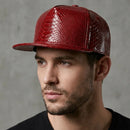 Man wearing a red snake skin textured cap against a gray background, Obroi