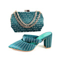 Teal handbag with chain detail and matching teal shoe on a white background, Obroi