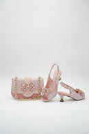 Pink high-heeled shoes and matching handbag with decorative elements on a white background, Obroi
