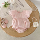 Pink baby romper with matching shoes on a wooden table, Obroi