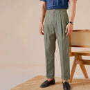 Person wearing green pants and a blue shirt in a casual setting with a wooden chair, Obroi