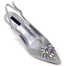 Silver high-heeled shoe with a colorful gemstone on a white background