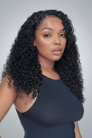 A black curly wig displayed on a mannequin head next to a woman wearing it. The wig features deep, glossy ringlets with a realistic hairline, Obroi