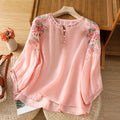 Pink floral blouse on a wooden hanger with a wooden floor background, Obroi