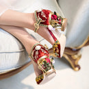 Obroi Decorative red and gold shoes with floral details on a light background
