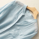 Light blue shirt on a wooden hanger against a beige background, Obroi