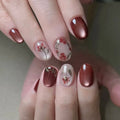 Close-up of a hand with maroon nail polish and floral designs on a neutral background, Obroi