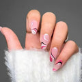 Hand with pink and black wavy nail art on a gray background, Obroi