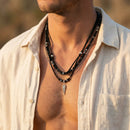 Man wearing a necklace with a blurred background, Obroi