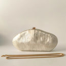 White marble-textured clutch bag with gold chain on a light gray background, Obroi