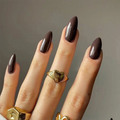 Hand with dark nail polish and gold rings on a neutral background, Obroi