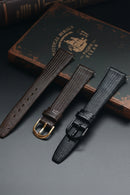 Two leather watch straps on a textured surface with a book in the background, Obroi