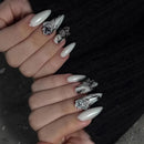 Close-up of a hand with long, almond-shaped nails featuring marble and floral designs, Obroi