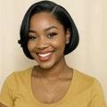 Woman with a short black bob hairstyle wearing a yellow shirt against a beige background, Obroi