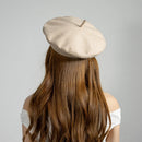 Person wearing a beige beret with long brown hair on a gray background, Obroi