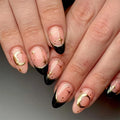 Nails with black, gold, and pink design on a neutral background, Obroi