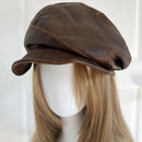 Brown leather cap on a mannequin head with blonde hair against a white background, Obroi